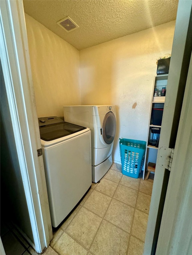 laundry area with independent washer and dryer and a textured ceiling