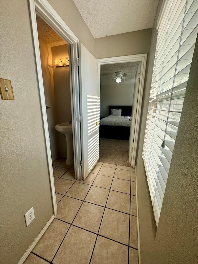 hall featuring a wealth of natural light, sink, light tile patterned floors, and a textured ceiling