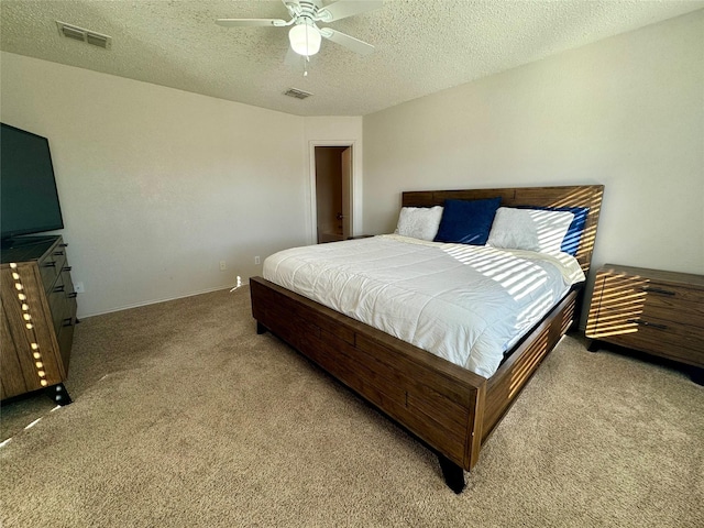 bedroom featuring a textured ceiling, light colored carpet, and ceiling fan