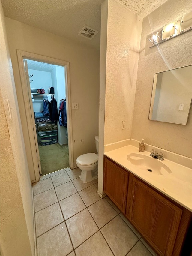 bathroom featuring tile patterned floors, toilet, a textured ceiling, and vanity