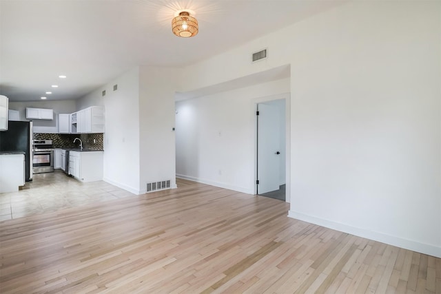 unfurnished living room with sink and light hardwood / wood-style floors