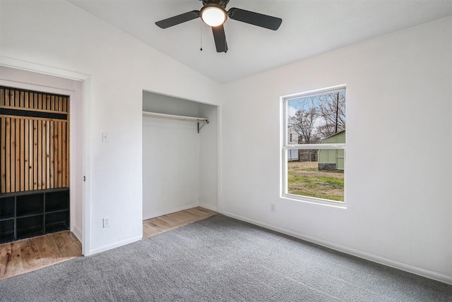 unfurnished bedroom with lofted ceiling, a closet, ceiling fan, and carpet flooring