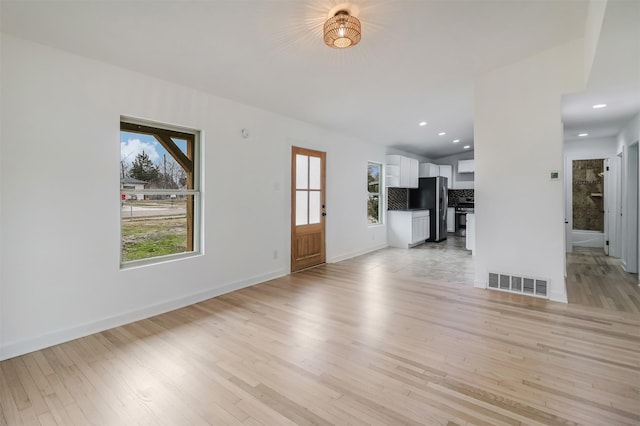 unfurnished living room featuring vaulted ceiling and light hardwood / wood-style floors