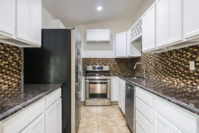 kitchen featuring appliances with stainless steel finishes, sink, white cabinets, dark stone counters, and decorative backsplash