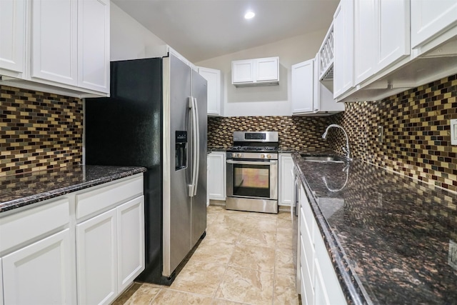 kitchen with sink, white cabinets, dark stone counters, decorative backsplash, and stainless steel appliances