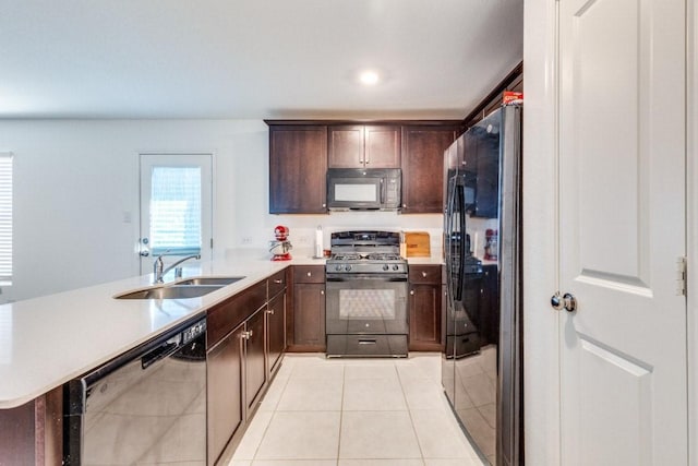 kitchen with sink, light tile patterned floors, dark brown cabinets, black appliances, and kitchen peninsula