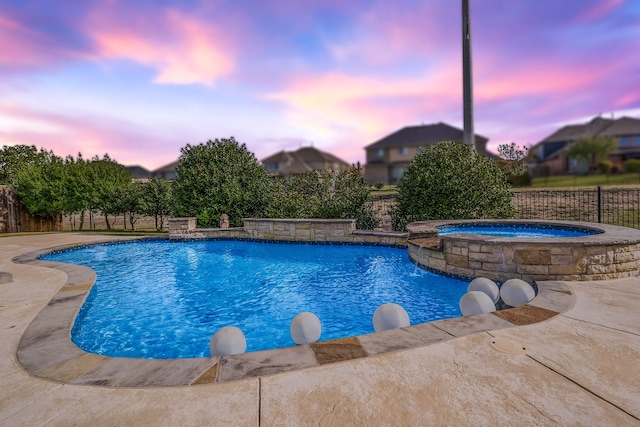 view of pool with fence and a pool with connected hot tub