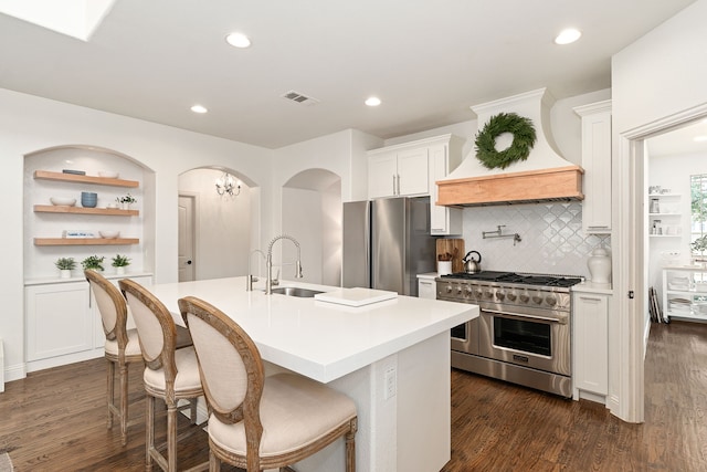 kitchen with visible vents, a sink, dark wood-type flooring, custom range hood, and appliances with stainless steel finishes