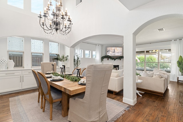 dining room featuring arched walkways, visible vents, an inviting chandelier, and wood finished floors