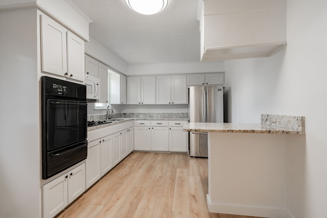 kitchen featuring sink, light hardwood / wood-style flooring, white cabinetry, light stone counters, and black appliances