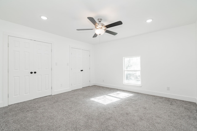 unfurnished bedroom with ceiling fan, carpet flooring, and two closets