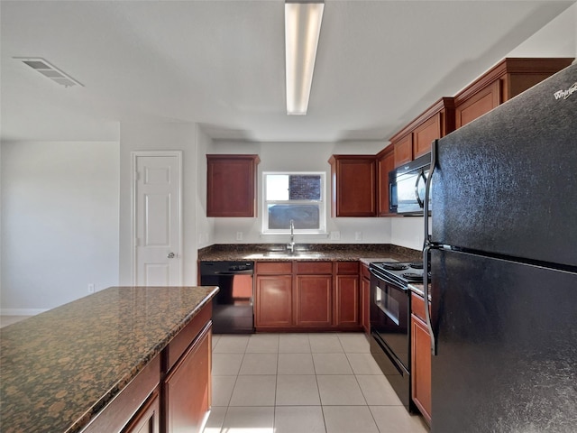 kitchen featuring dark stone countertops, sink, black appliances, and light tile patterned flooring