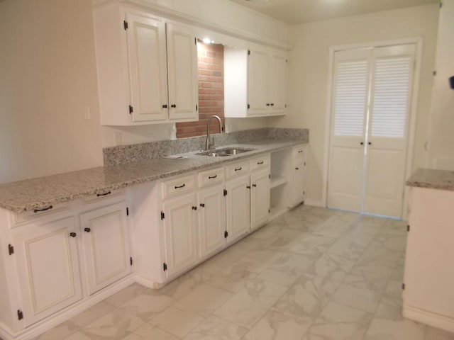 kitchen with white cabinets, sink, and light stone counters