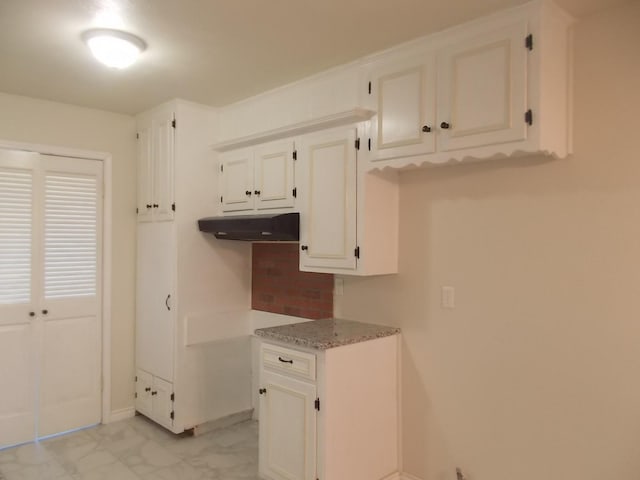 kitchen with white cabinets, light stone countertops, and tasteful backsplash