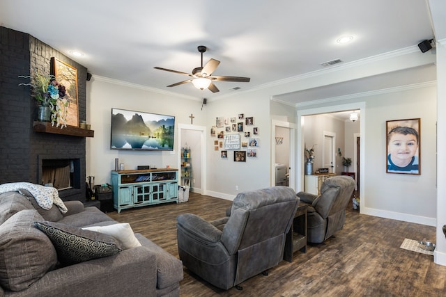 living room with crown molding, a brick fireplace, dark wood-type flooring, and ceiling fan