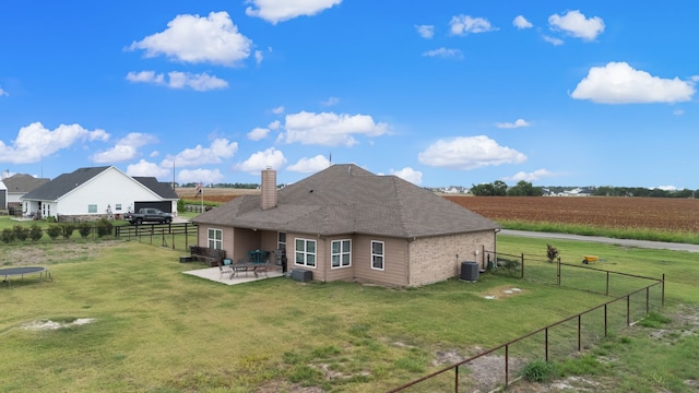 back of house featuring a rural view, cooling unit, a lawn, and a patio