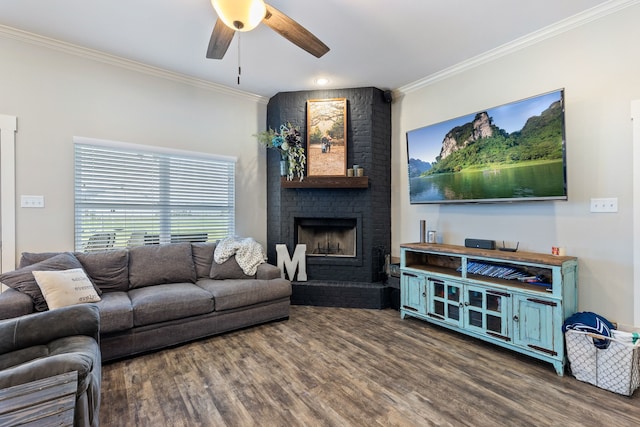 living room with crown molding, ceiling fan, a fireplace, and dark wood-type flooring