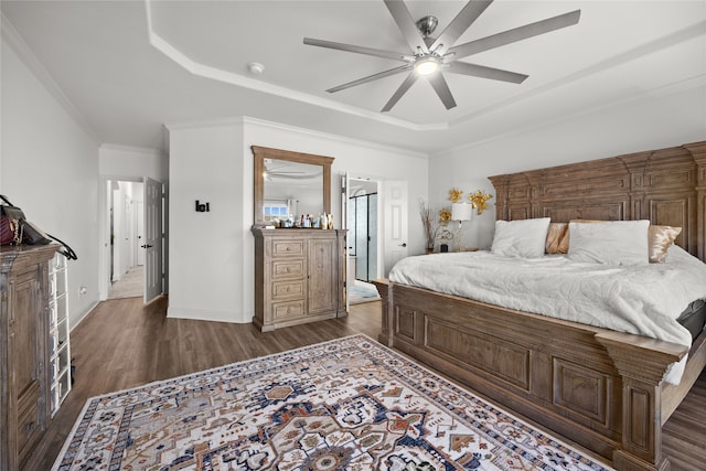 bedroom featuring dark wood-type flooring, ceiling fan, ornamental molding, and a raised ceiling