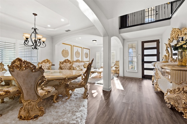 dining area featuring a tray ceiling, dark wood-type flooring, a chandelier, and a healthy amount of sunlight