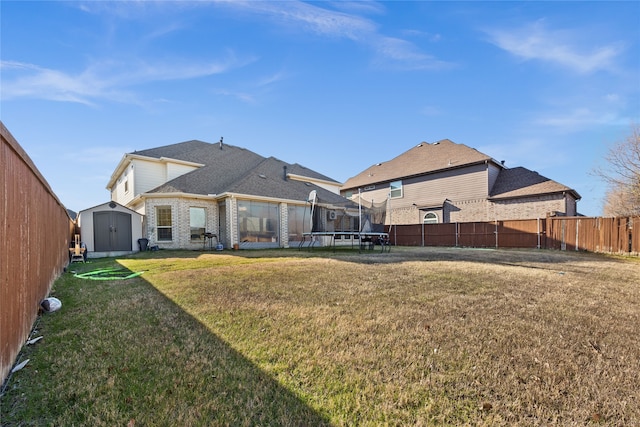 rear view of house with a yard, a trampoline, and a storage unit