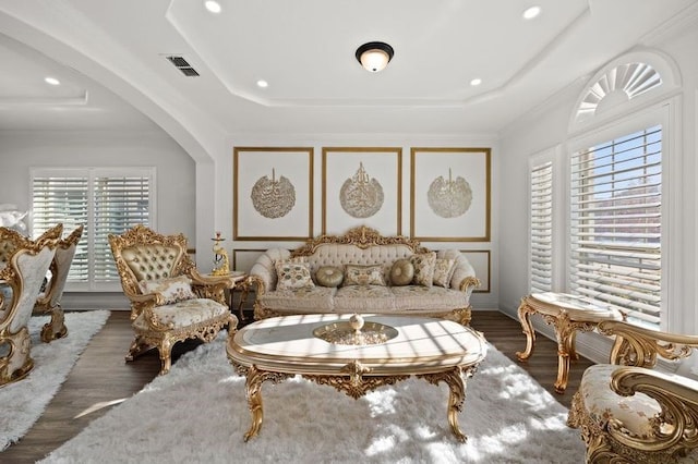 living area featuring dark hardwood / wood-style floors, a tray ceiling, and crown molding