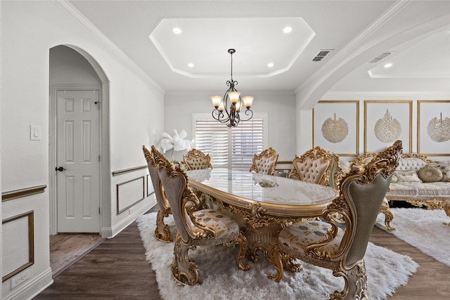 dining area featuring crown molding, dark hardwood / wood-style flooring, a raised ceiling, and a notable chandelier