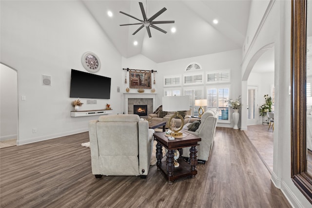 living room with dark hardwood / wood-style flooring, ceiling fan, and high vaulted ceiling