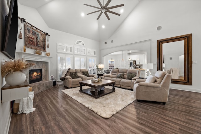 living room featuring dark hardwood / wood-style flooring, a fireplace, high vaulted ceiling, and ceiling fan