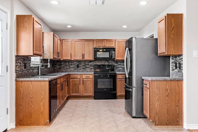 kitchen featuring light tile patterned flooring, a sink, visible vents, decorative backsplash, and black appliances