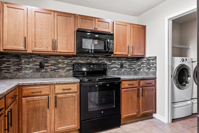 kitchen featuring light tile patterned flooring, decorative backsplash, black appliances, brown cabinetry, and washing machine and clothes dryer