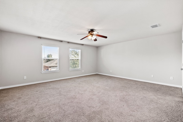 carpeted empty room featuring baseboards, visible vents, and a ceiling fan