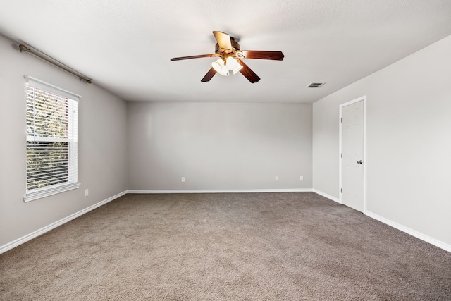 empty room with a ceiling fan, carpet flooring, visible vents, and baseboards