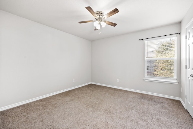 carpeted empty room with a ceiling fan and baseboards