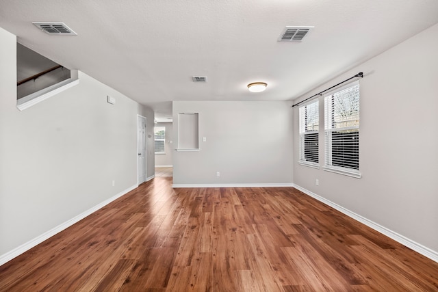 unfurnished room featuring visible vents, baseboards, and wood finished floors