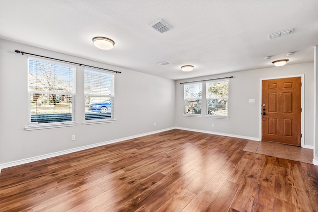 interior space featuring plenty of natural light, wood finished floors, visible vents, and baseboards