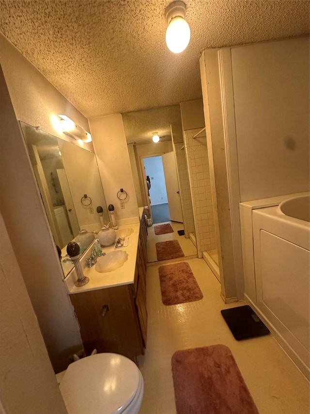 bathroom featuring vanity, washer / clothes dryer, a textured ceiling, and a shower