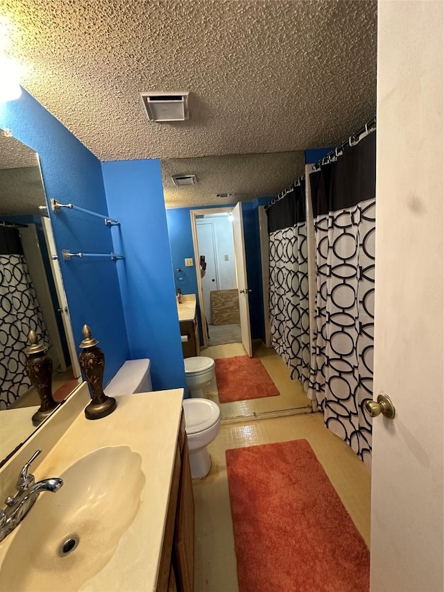 bathroom featuring vanity, toilet, and a textured ceiling