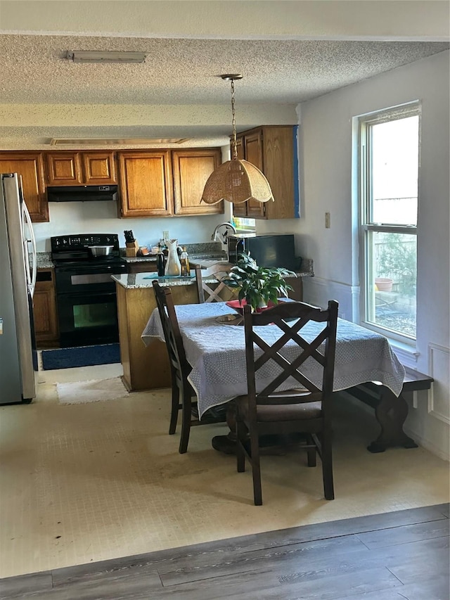 kitchen featuring stainless steel refrigerator, decorative light fixtures, sink, double oven range, and a textured ceiling