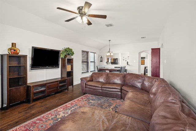 living room with ceiling fan with notable chandelier, dark hardwood / wood-style flooring, and vaulted ceiling