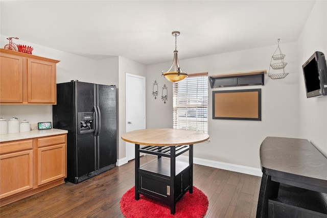 kitchen with hanging light fixtures, dark wood-type flooring, and black refrigerator with ice dispenser