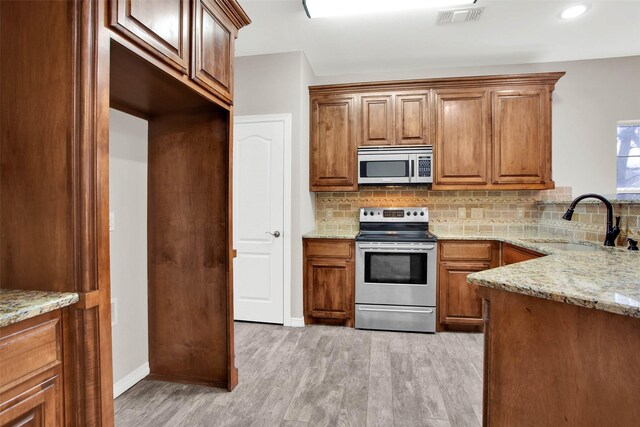 kitchen featuring ceiling fan, backsplash, appliances with stainless steel finishes, light stone countertops, and a sink