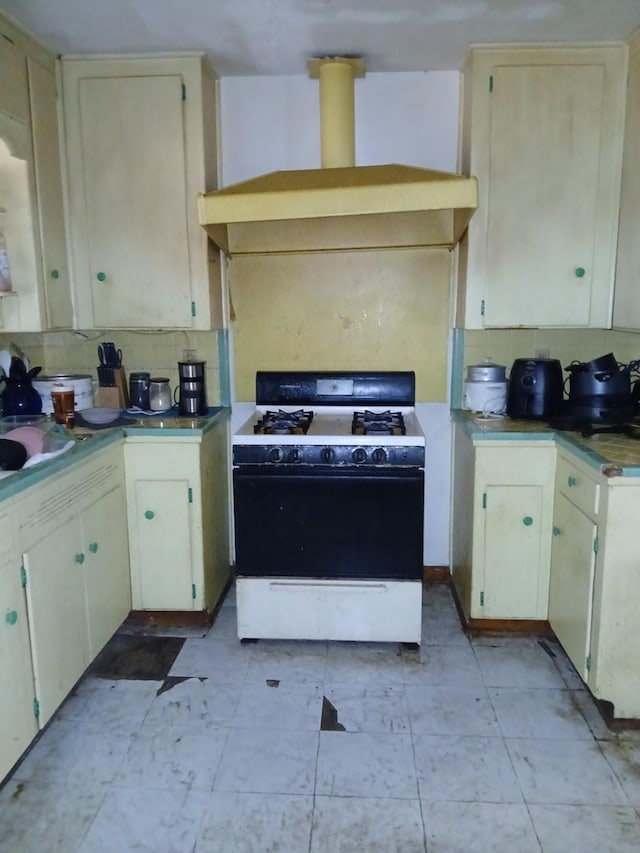 kitchen with sink, white gas range oven, tasteful backsplash, cream cabinets, and ventilation hood