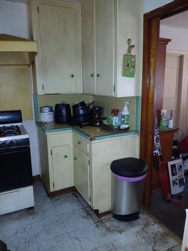 kitchen with decorative backsplash, gas stove, and white cabinets