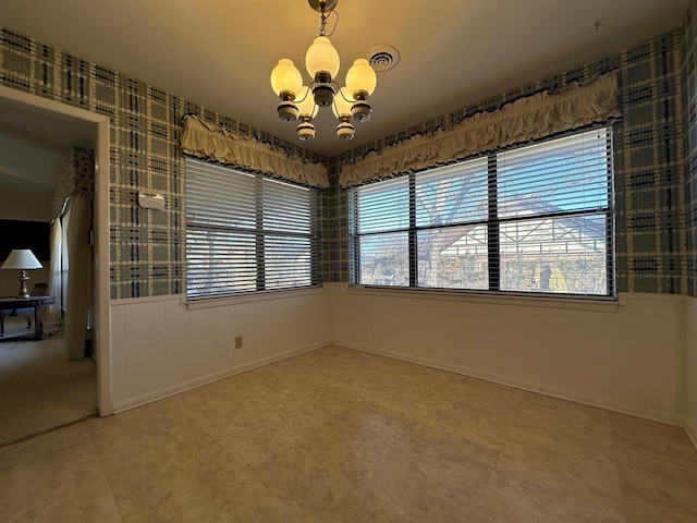 tiled spare room featuring an inviting chandelier