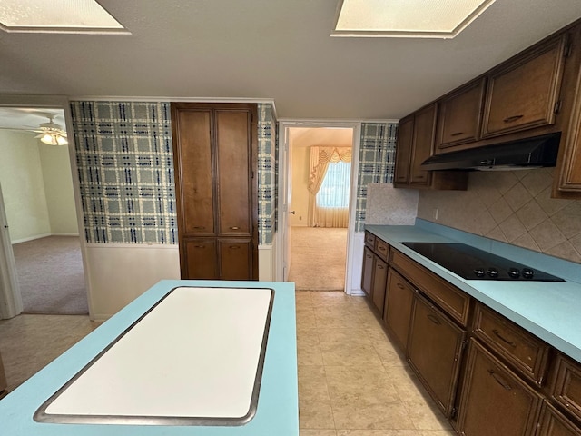 kitchen featuring ceiling fan, dark brown cabinetry, black electric cooktop, decorative backsplash, and light colored carpet