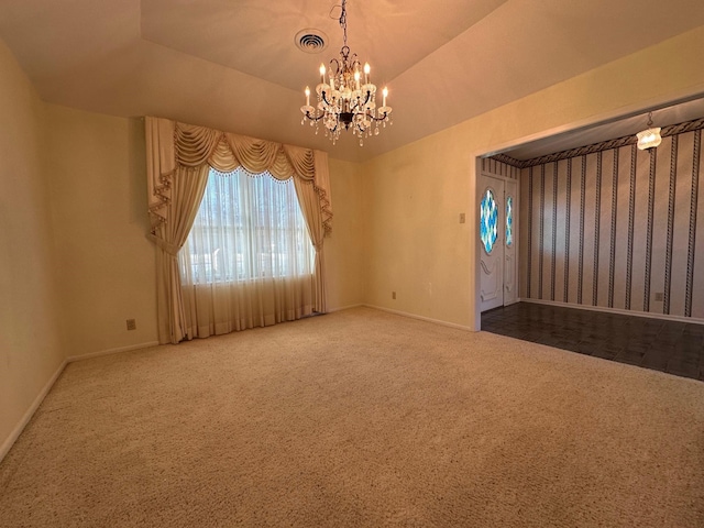 empty room with lofted ceiling, a tray ceiling, a chandelier, and carpet