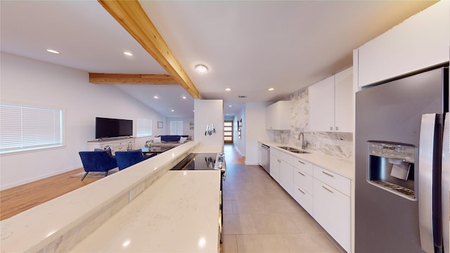 kitchen featuring sink, vaulted ceiling with beams, appliances with stainless steel finishes, decorative backsplash, and white cabinets