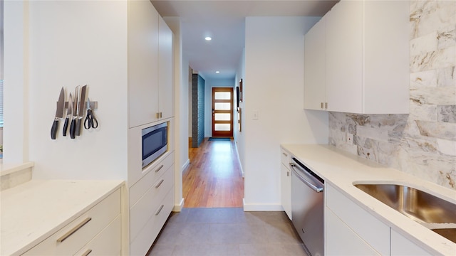 kitchen featuring stainless steel appliances, white cabinetry, sink, and decorative backsplash