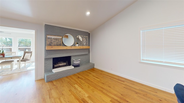 unfurnished living room with hardwood / wood-style flooring, a large fireplace, and lofted ceiling