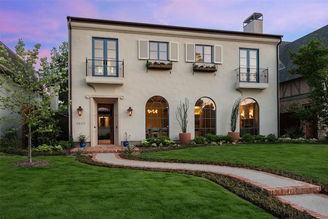 view of front of property featuring a balcony and a yard